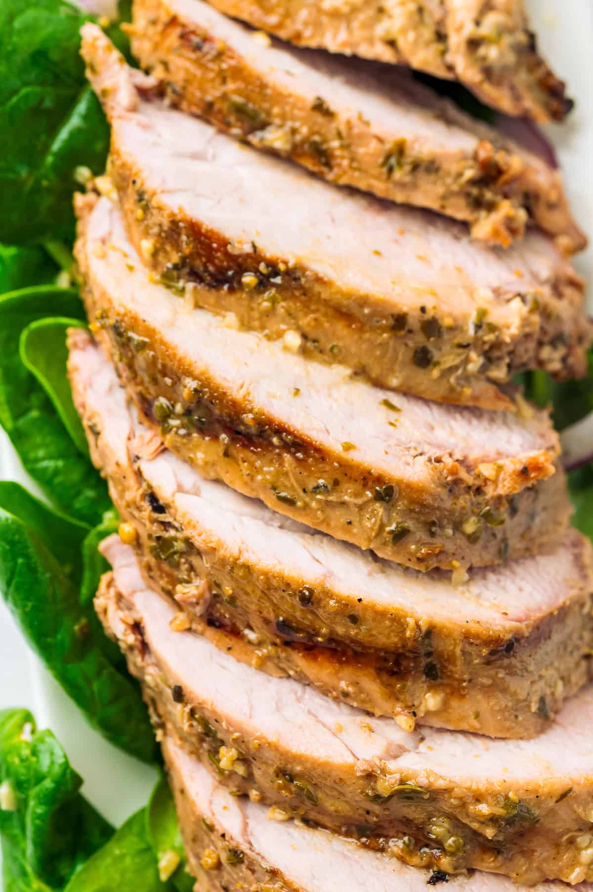 Sliced grilled pork tenderloin showing a juicy center on a cutting board.