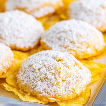Powdered sugar dusted potato chip cookies on a baking tray.