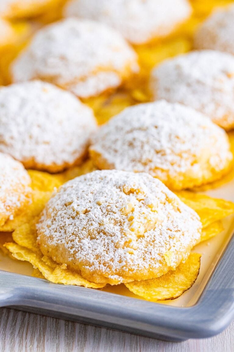 Powdered sugar dusted potato chip cookies on a baking tray.