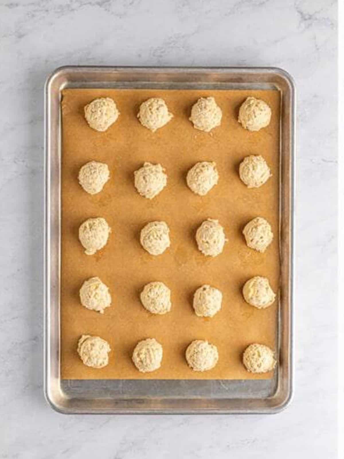 Dollops of cookie dough on a parchment-lined baking sheet.