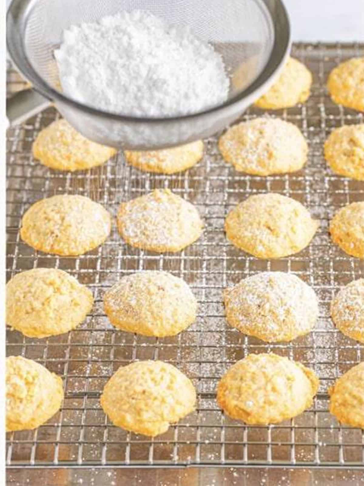 Baked potato chip cookies on a rack being dusted with powdered sugar.