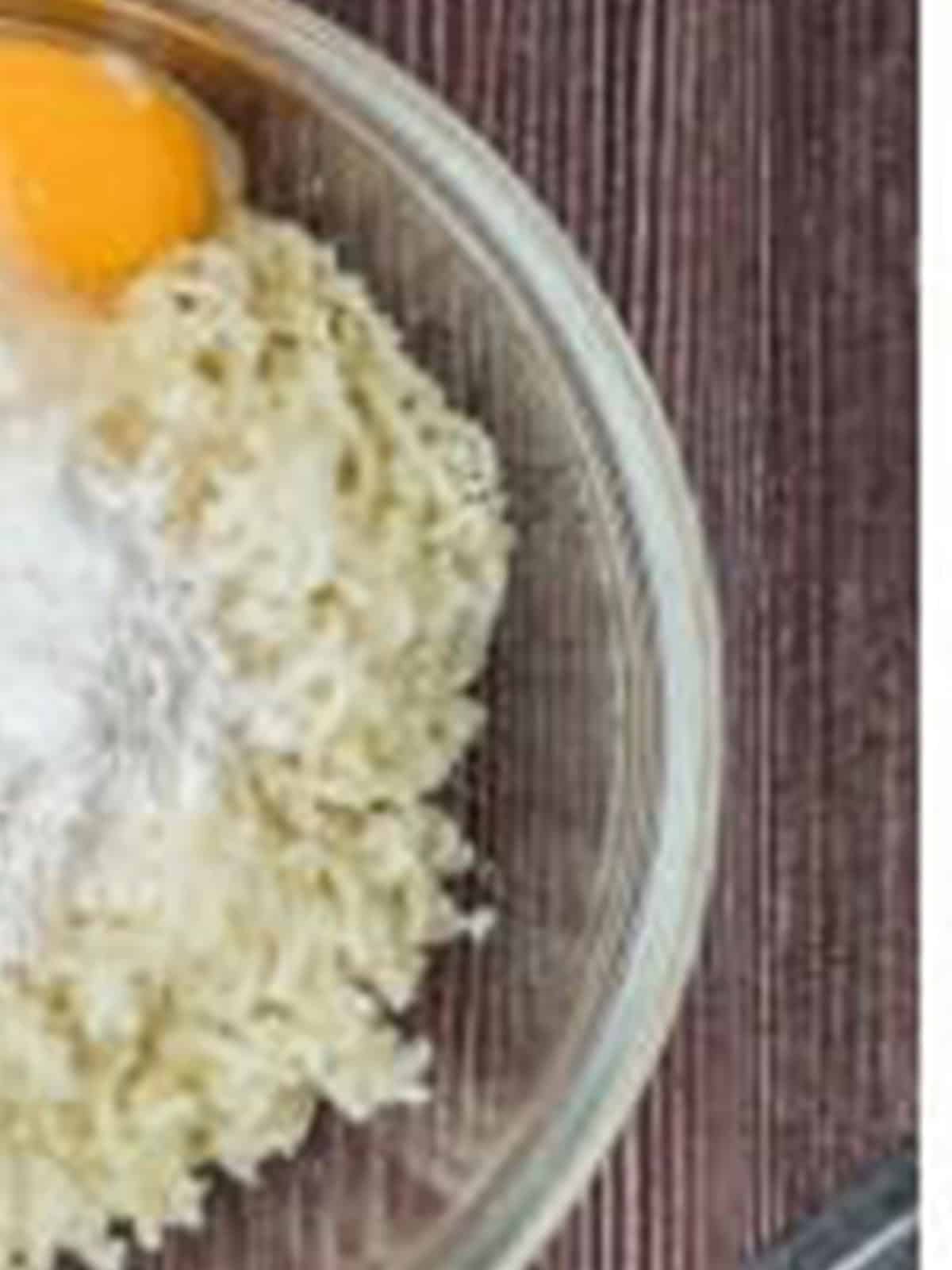Egg, flour, and salt added to riced potatoes in a bowl to make potato gnocchi dough.