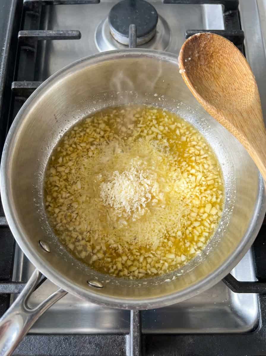 Garlic butter sauce with parmesan melting in a saucepan for potato wedges.