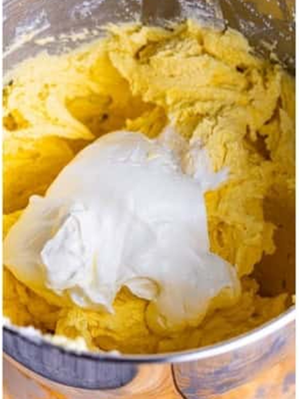Adding sour cream to pound cake batter in a mixer bowl