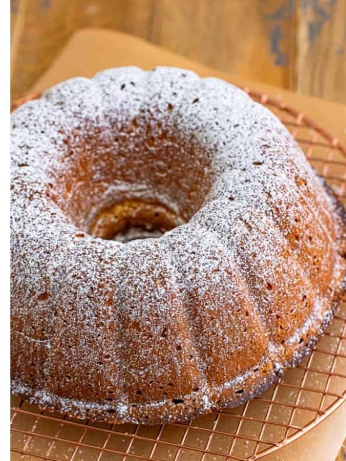 Baked pound cake dusted with powdered sugar on a wire rack