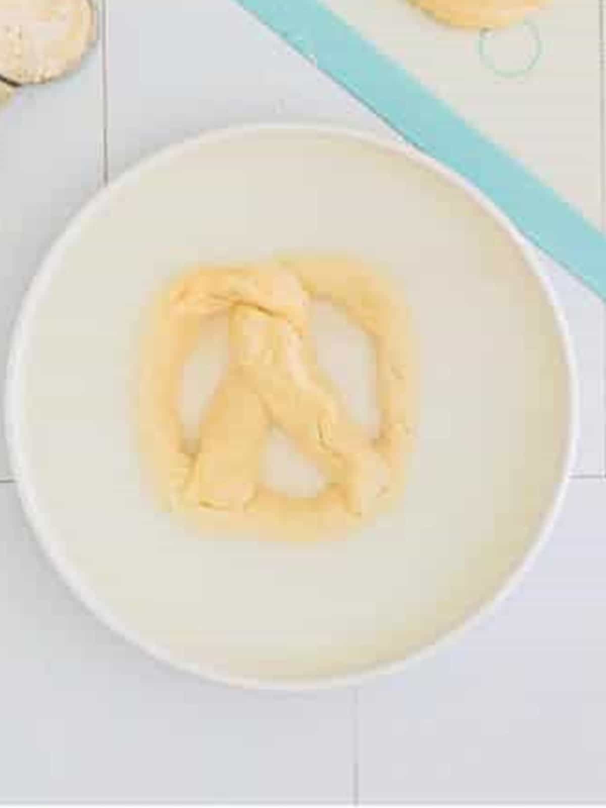 A shaped pretzel dipped into a baking soda water bath before baking.