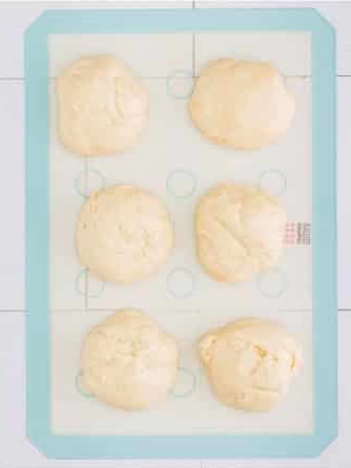 Pretzel dough divided into six equal portions on a baking tray.