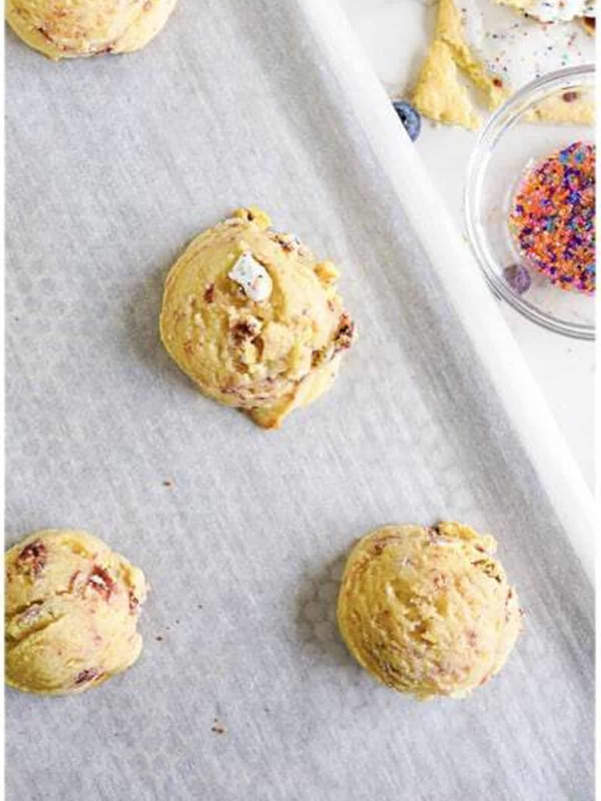 Scooped sugar cookie dough balls on a parchment-lined baking sheet.