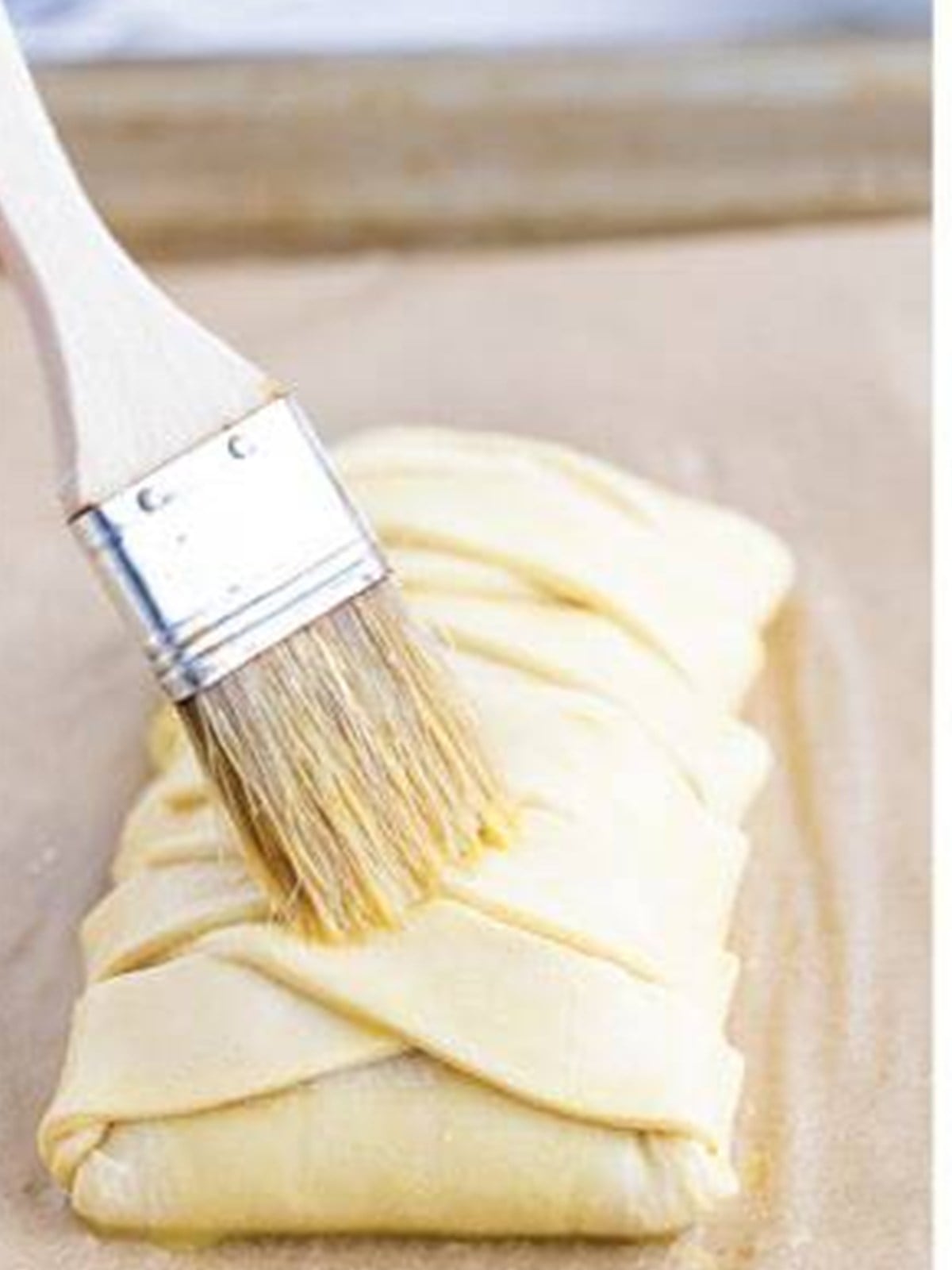 Egg wash brushed over the assembled puff pastry braid.