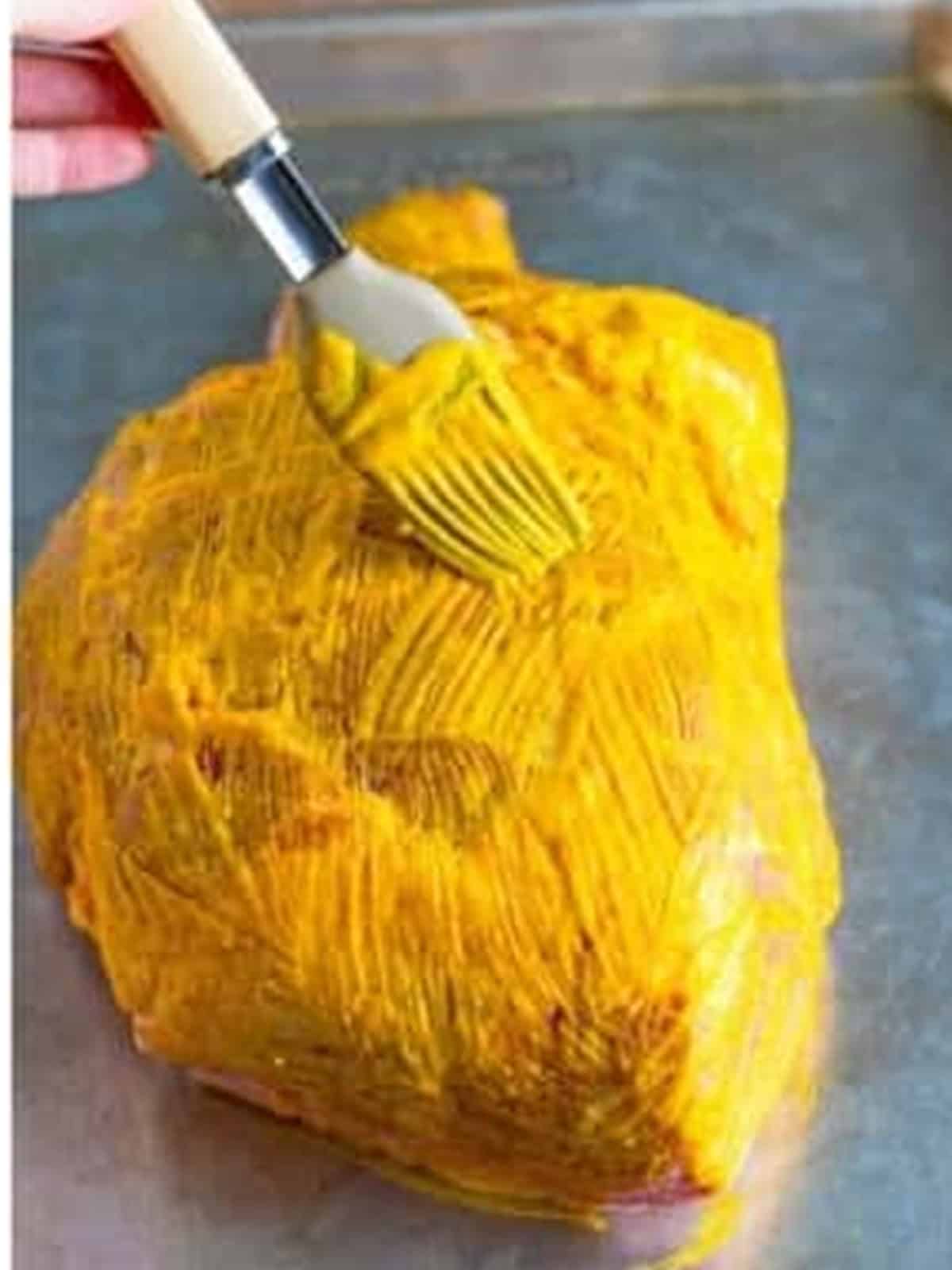 Brushing the pork shoulder all over with yellow mustard for the pulled pork recipe.