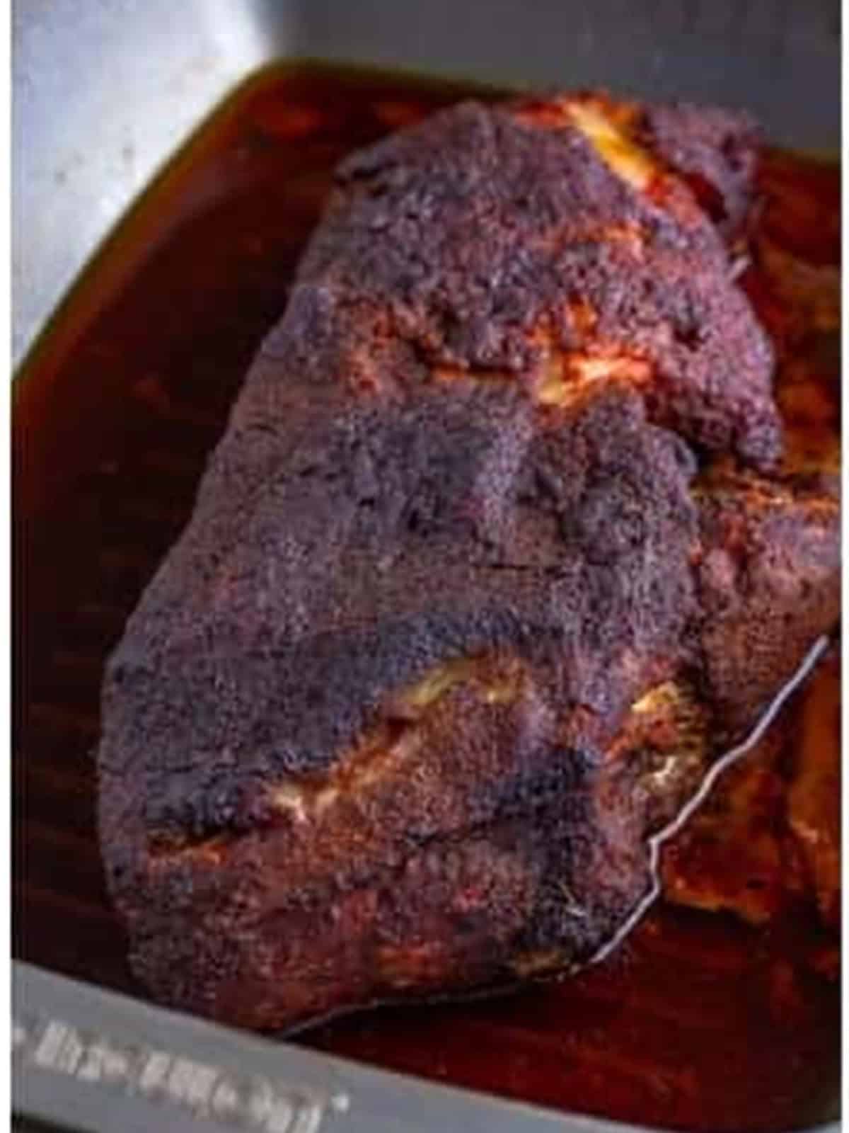 A dark, smoked pork shoulder with a deep bark after smoking for the pulled pork recipe.