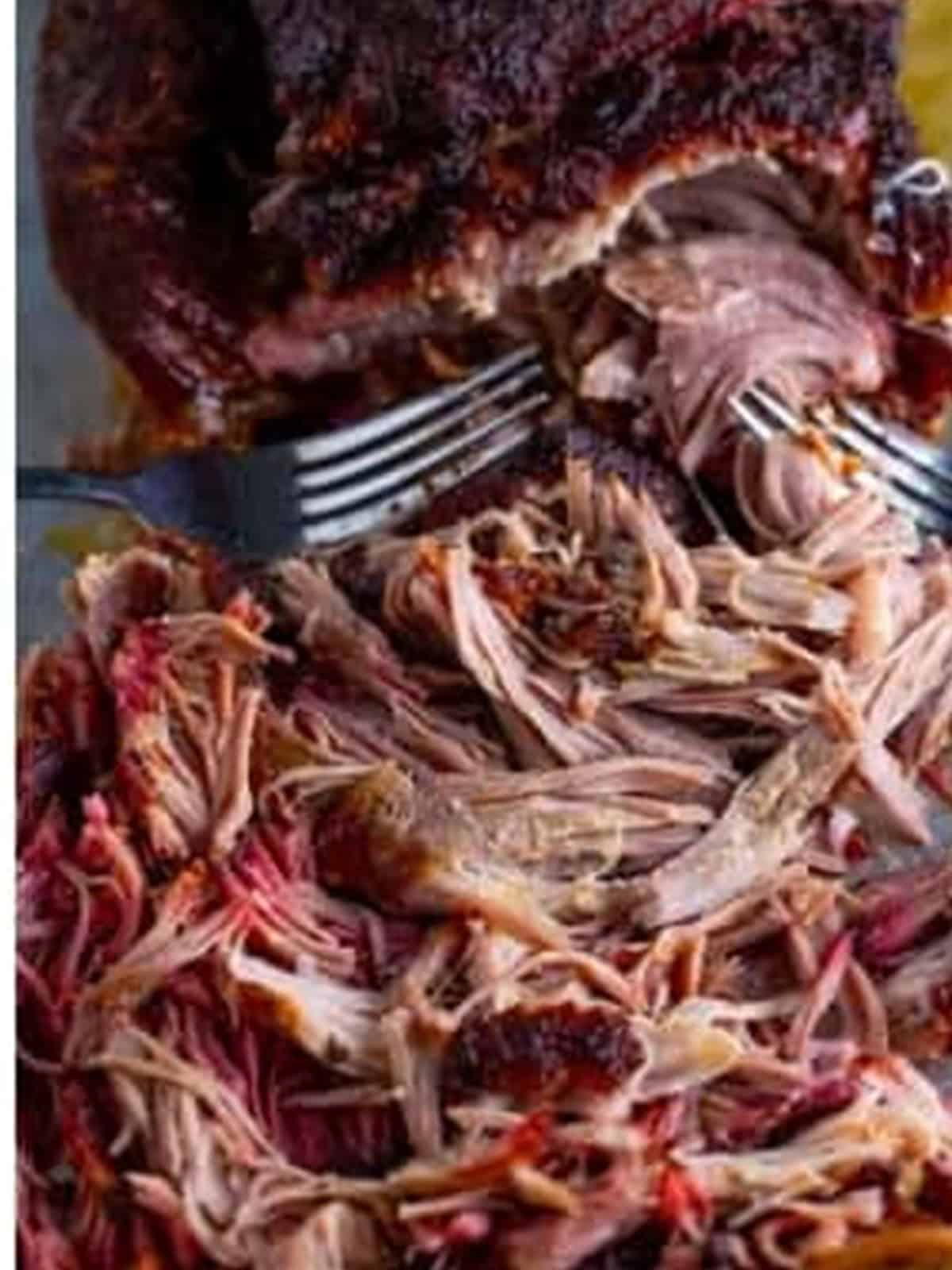 Tender smoked pork shoulder shredded into pulled pork with two forks.