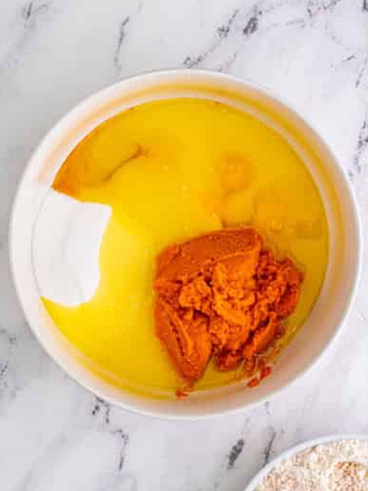 Mixing pumpkin puree, oil, eggs, and sugar in a bowl for pumpkin bars.