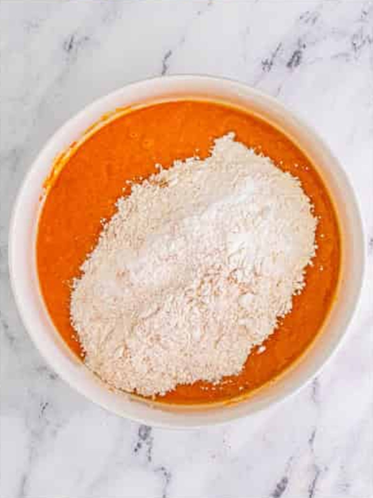 Adding flour and spices to the wet pumpkin batter.