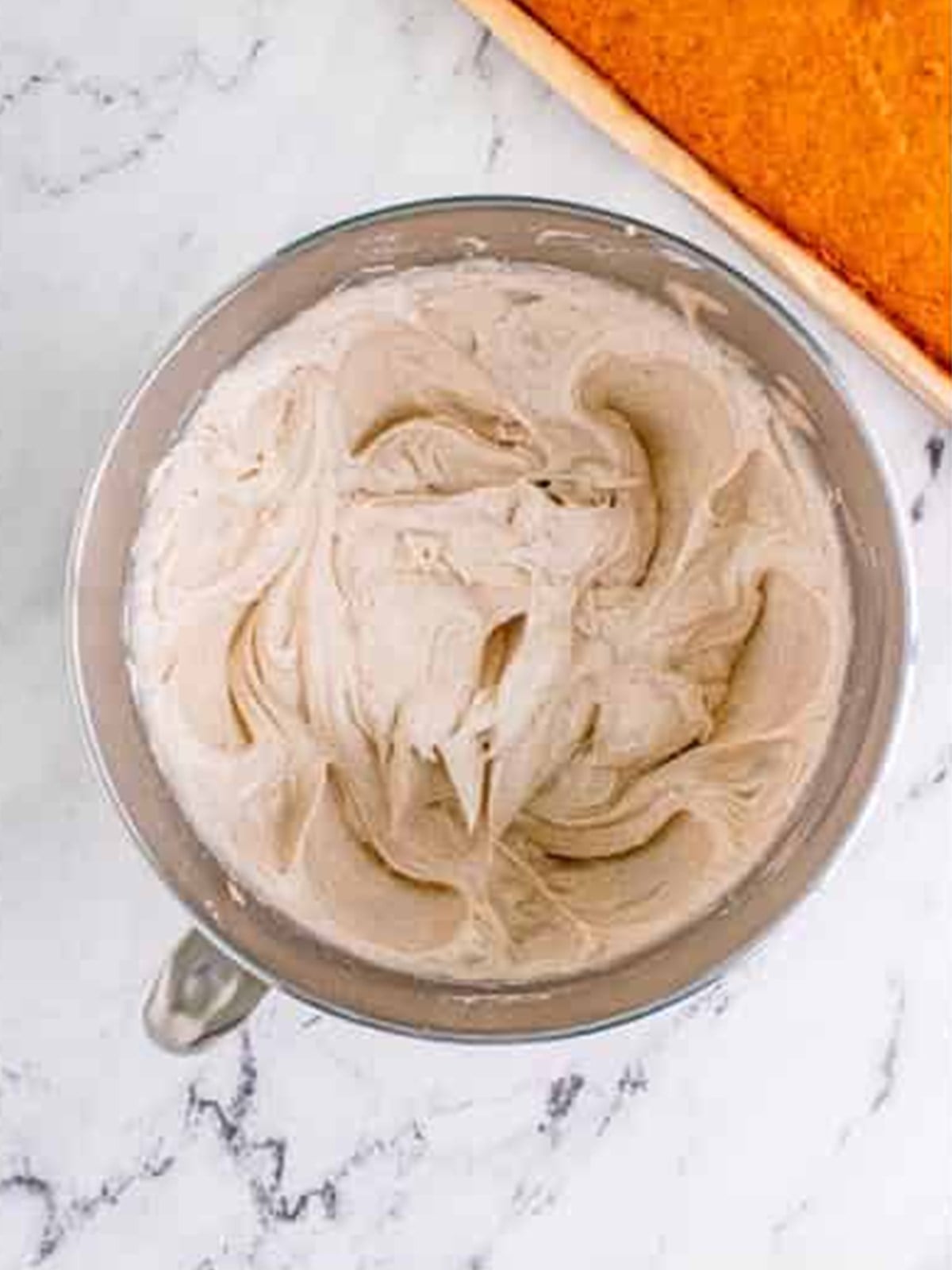 Whipping cream cheese frosting in a mixing bowl for pumpkin bars.