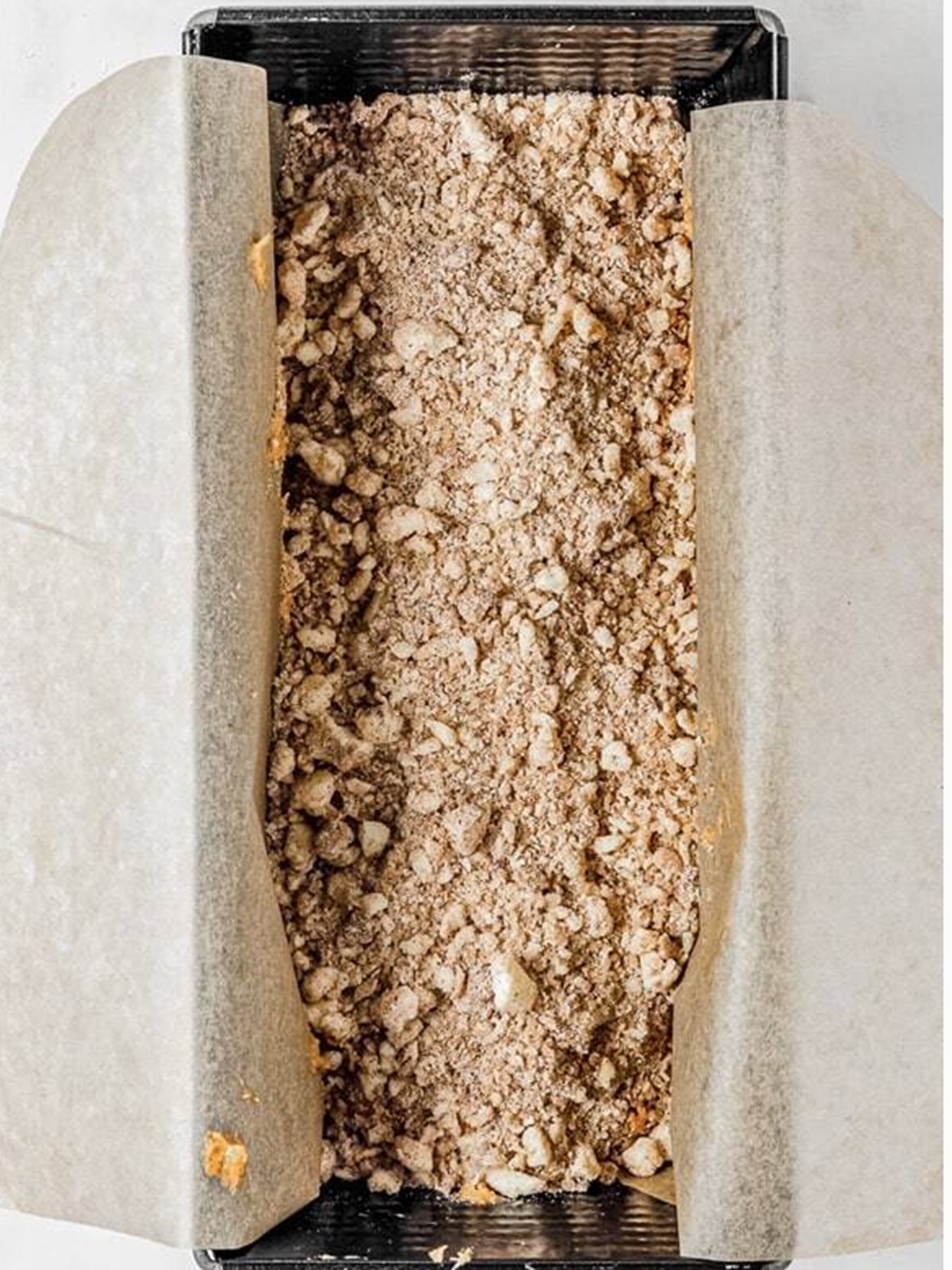 Pumpkin bread batter layered with streusel in a loaf pan