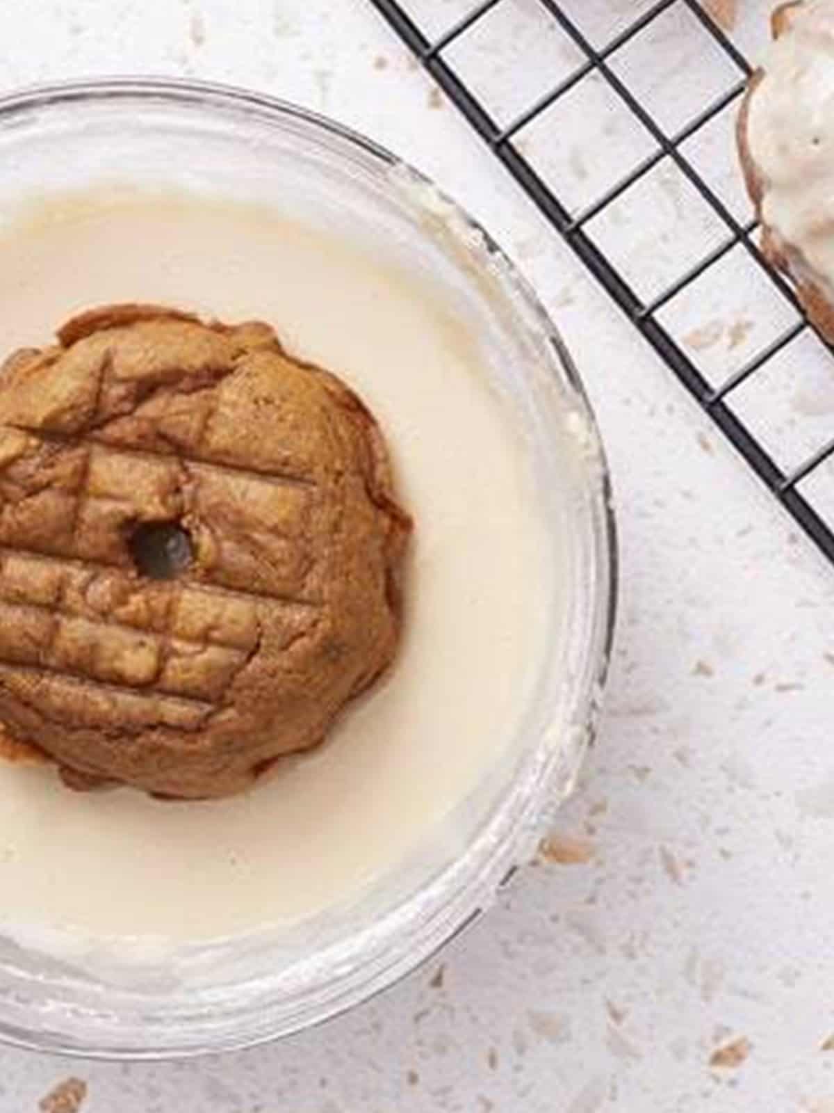 Dipping a mini pumpkin bundt cake into maple glaze.