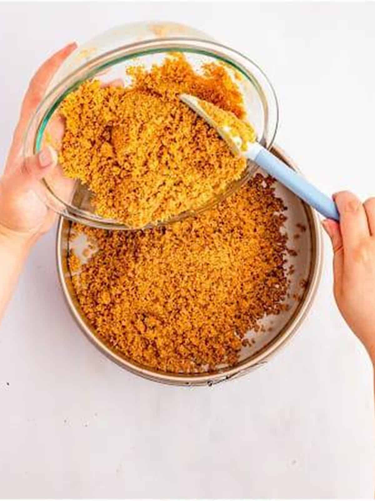 Pressing the graham cracker crust into a springform pan for pumpkin cheesecake.