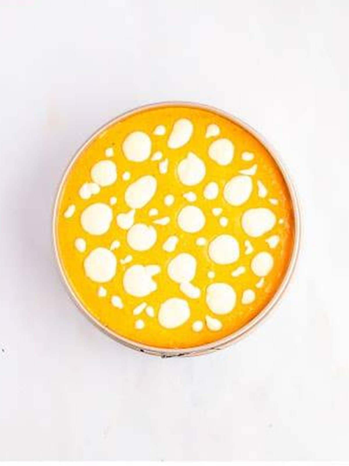 Dolloping plain cheesecake batter over the pumpkin layer to create swirls.