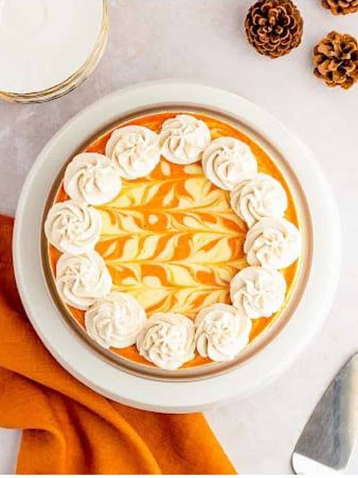 Finished swirled pumpkin cheesecake topped with piped cinnamon whipped cream rosettes.