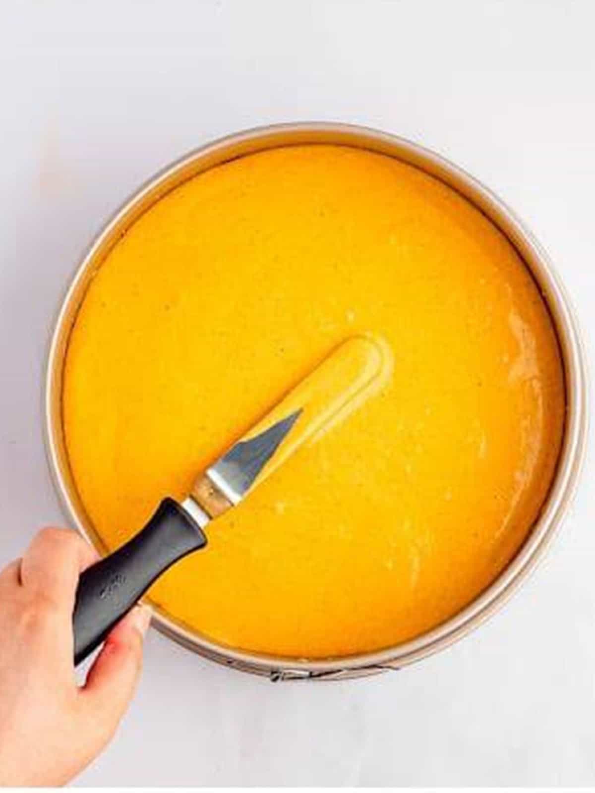 Smoothing the pumpkin cheesecake batter into the crust-lined pan.
