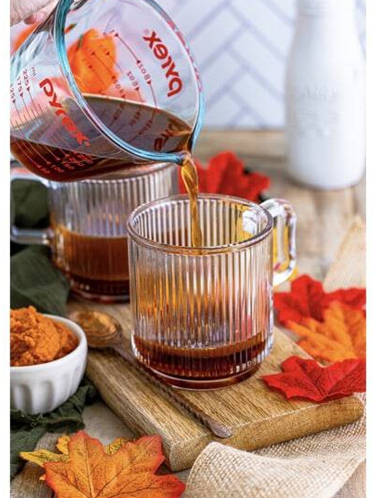 Hot coffee poured into the pumpkin mixture in a glass mug.