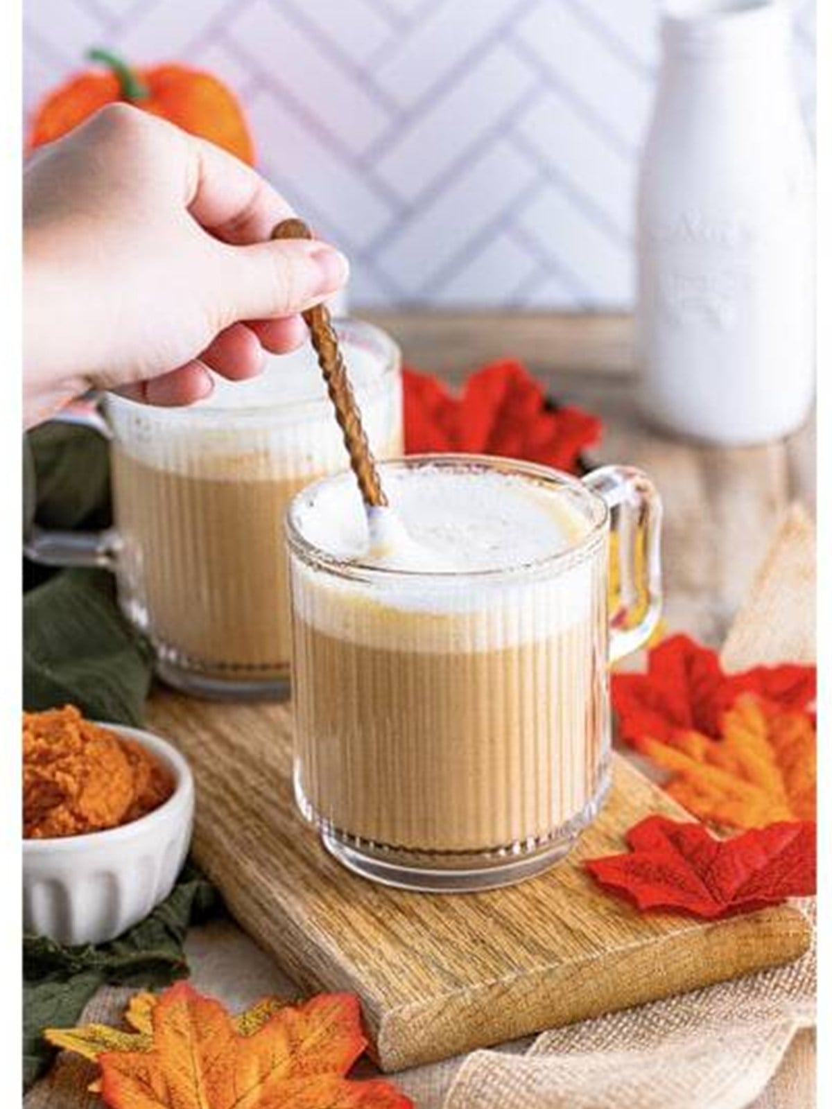 Pumpkin spice latte stirred together in a glass mug.