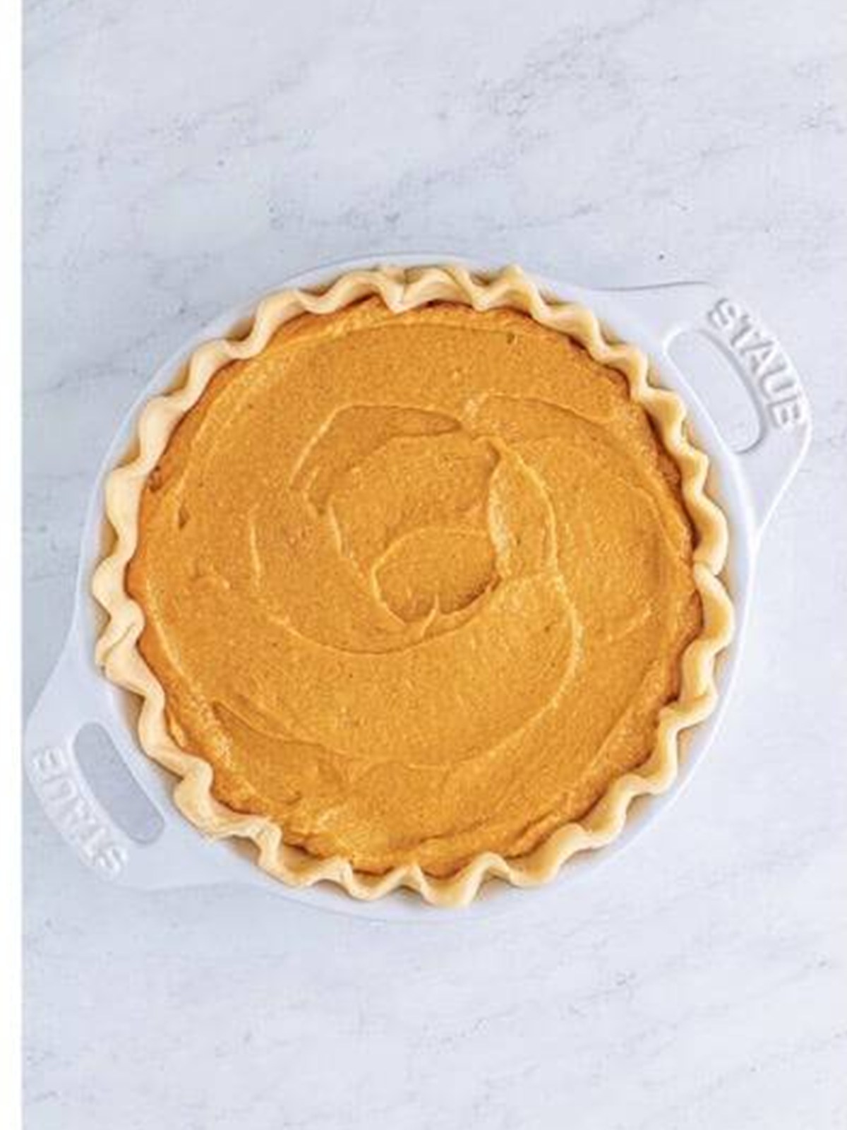 Pouring sweet potato pie filling into a pie crust.