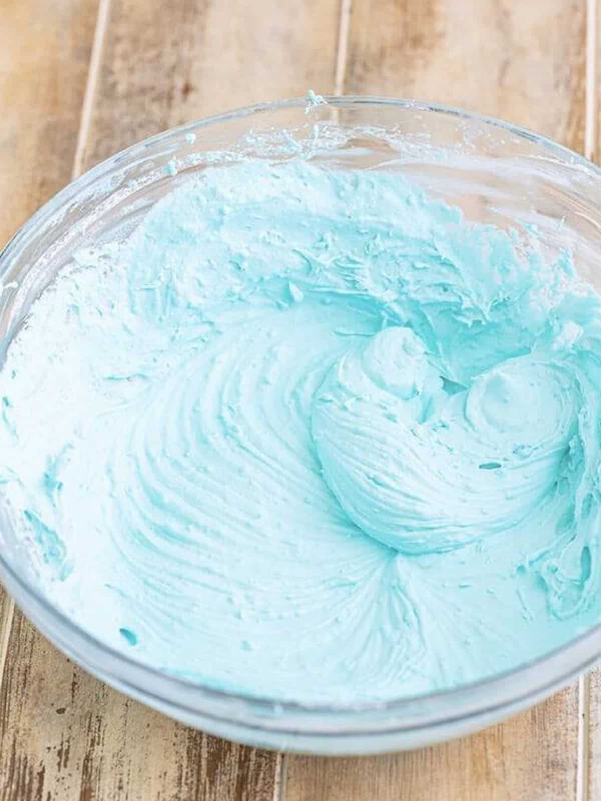 Whipped blue jello frosting in a glass bowl.