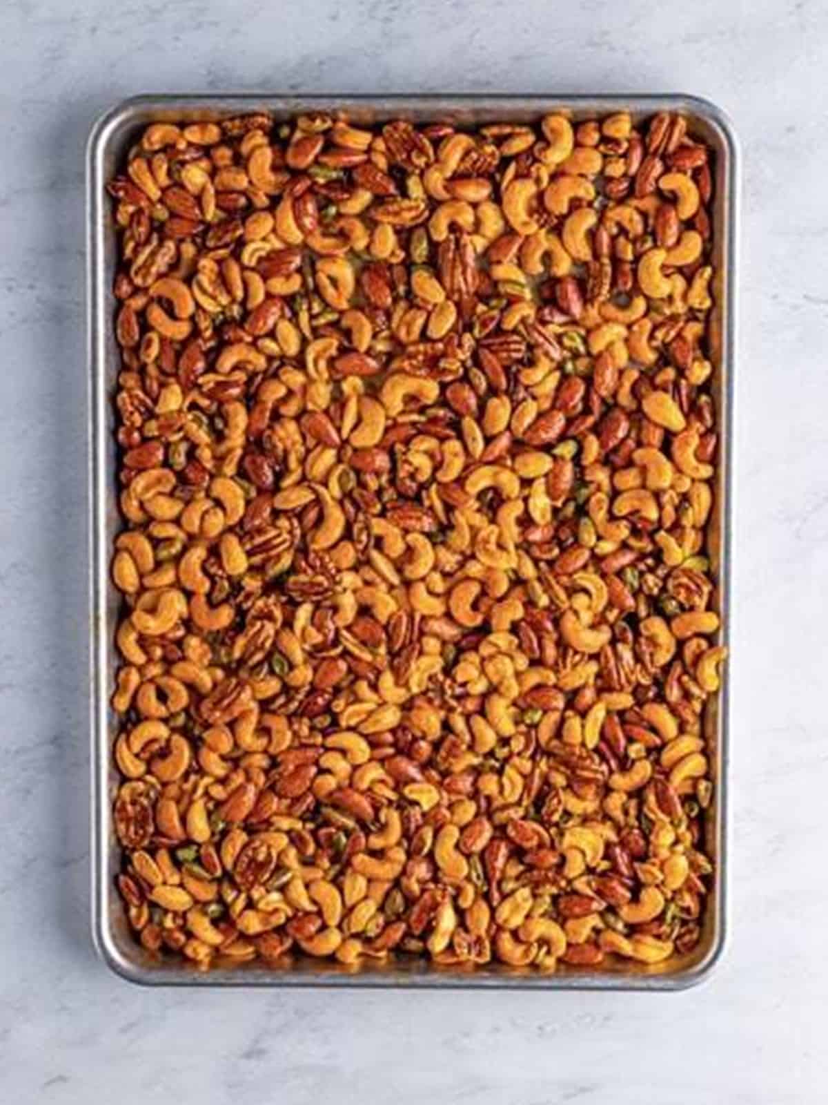 Coated nuts spread in an even layer on a sheet tray.