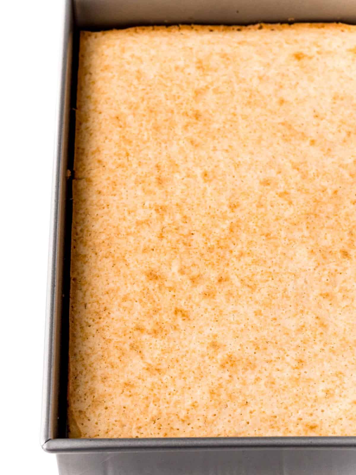 Baked white cake in a pan for Raspberry Poke Cake.
