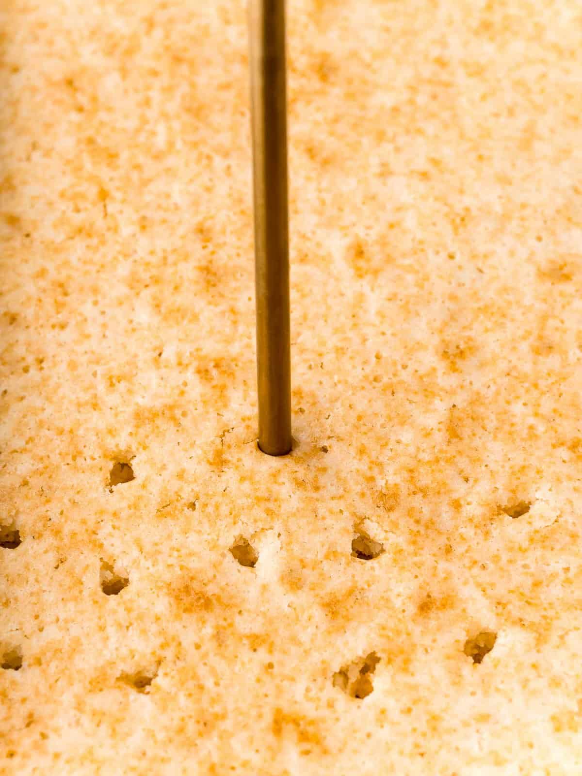 Poking holes in the baked cake for Raspberry Poke Cake.