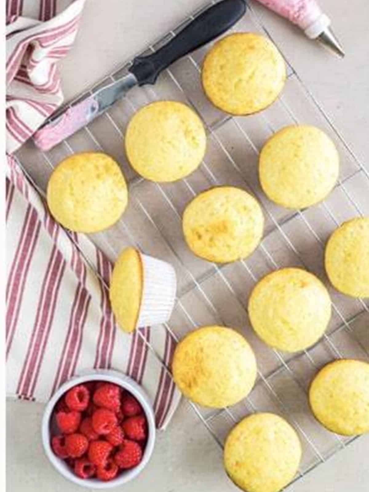 Baked almond cupcakes cooling on a wire rack.