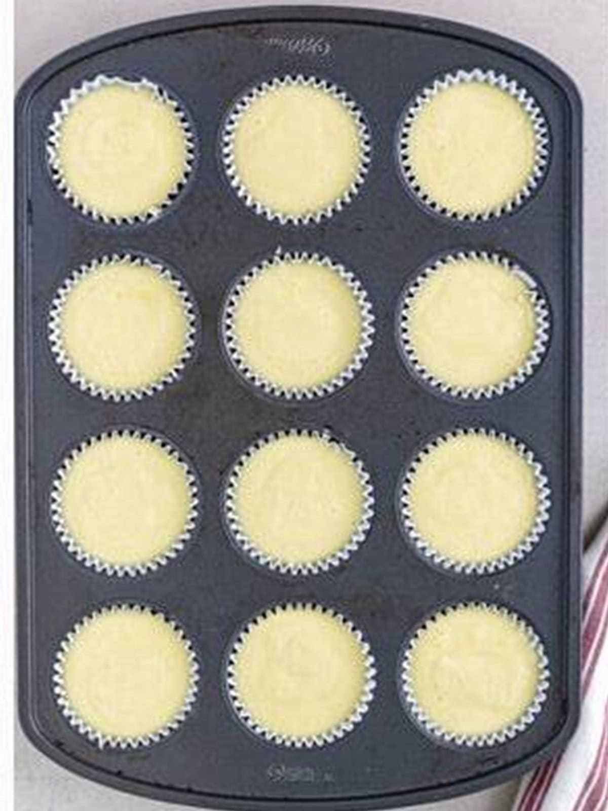 Almond cupcake batter portioned into a lined cupcake tin.