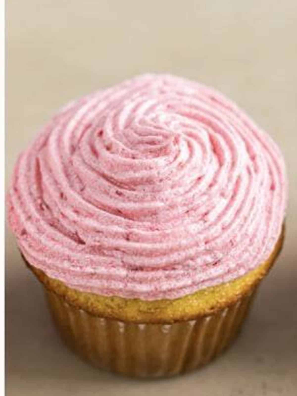 An almond cupcake frosted with a swirl of fresh raspberry buttercream.