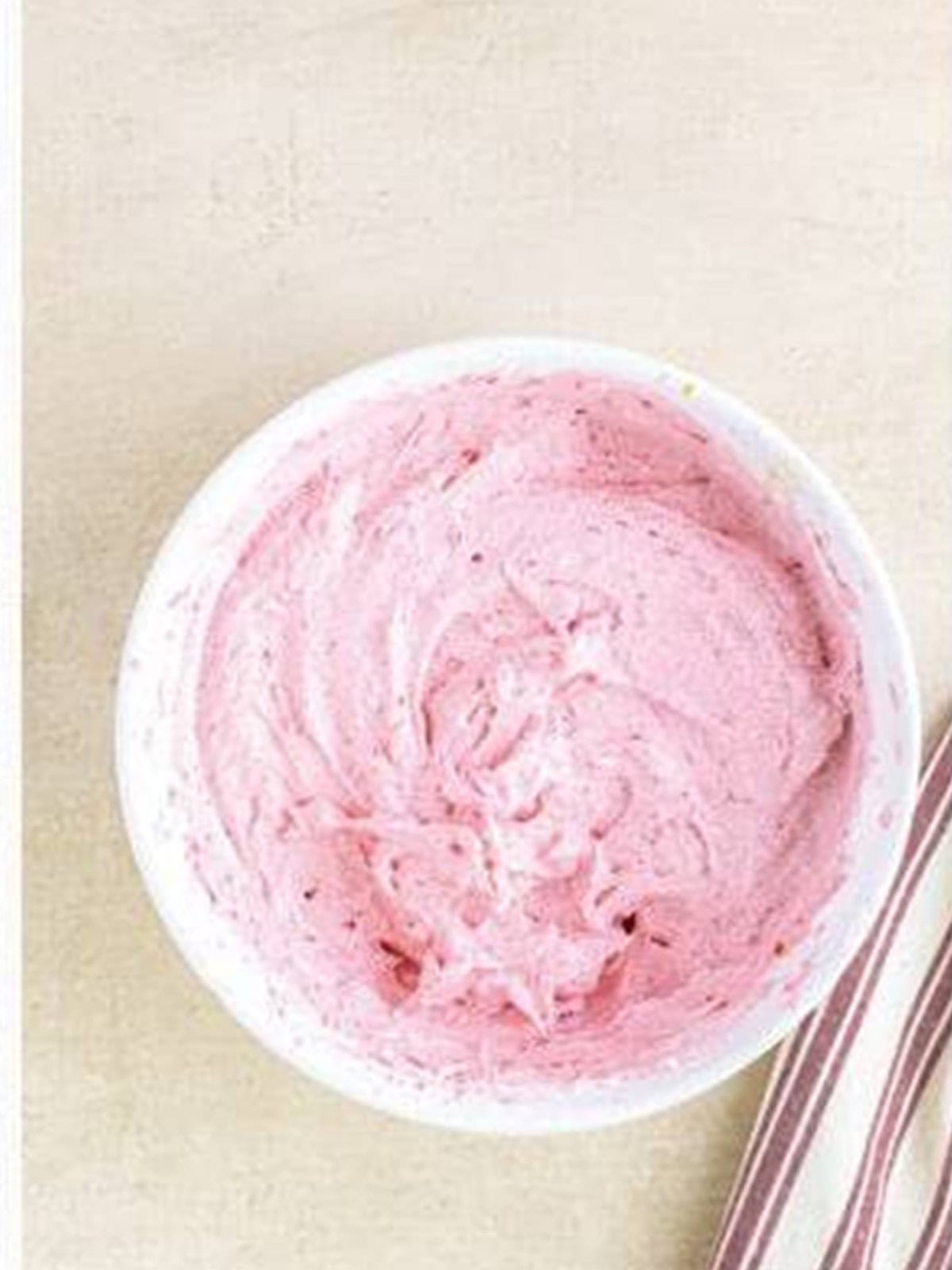 Fresh raspberry buttercream whipped smooth and pink in a bowl.