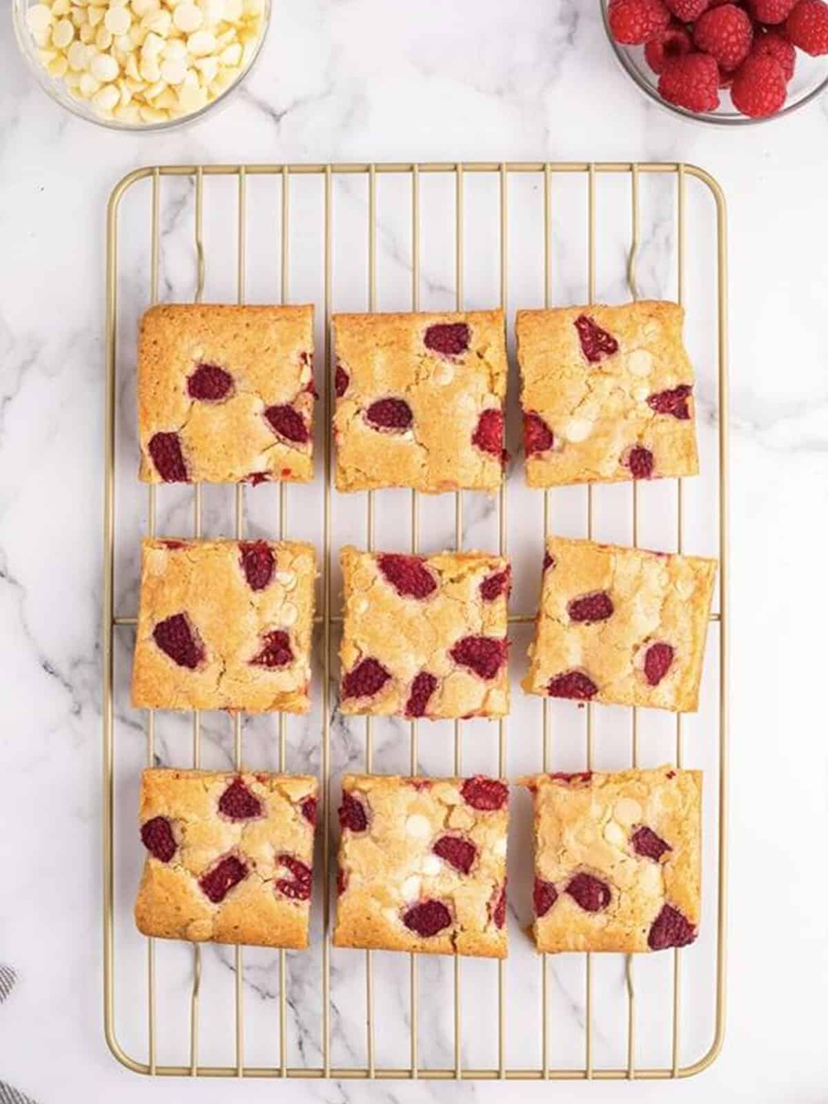 Baked raspberry white chocolate blondies sliced on a wire rack.