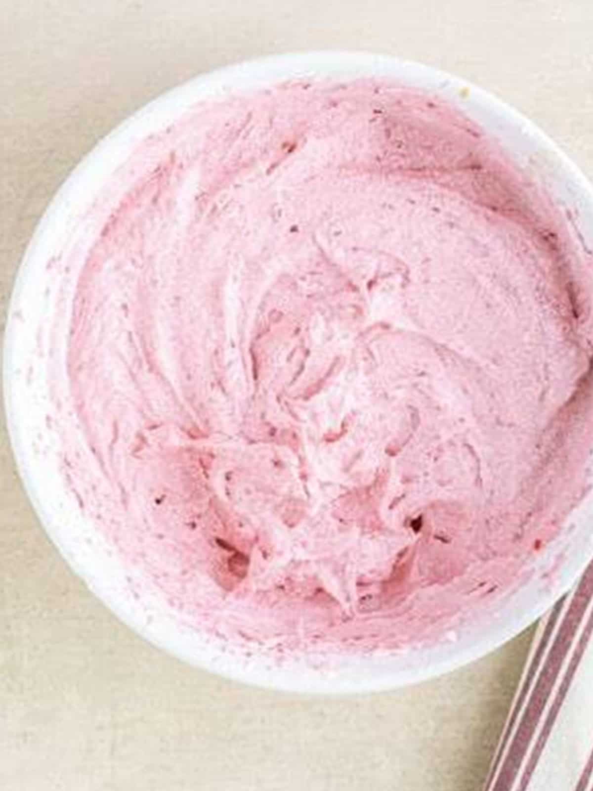 Fluffy pink raspberry frosting whipped smooth in a bowl.