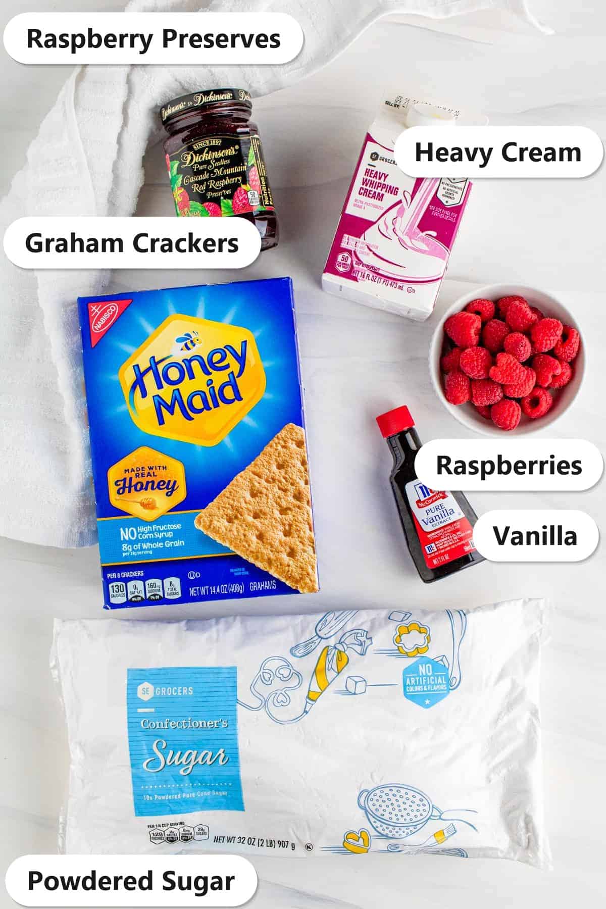 Ingredients to make a Raspberry Icebox Cake laid out and labeled on a white cloth.