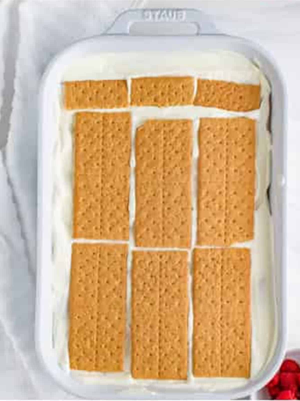 Final graham cracker layer added before the last cream layer on Raspberry Icebox Cake.