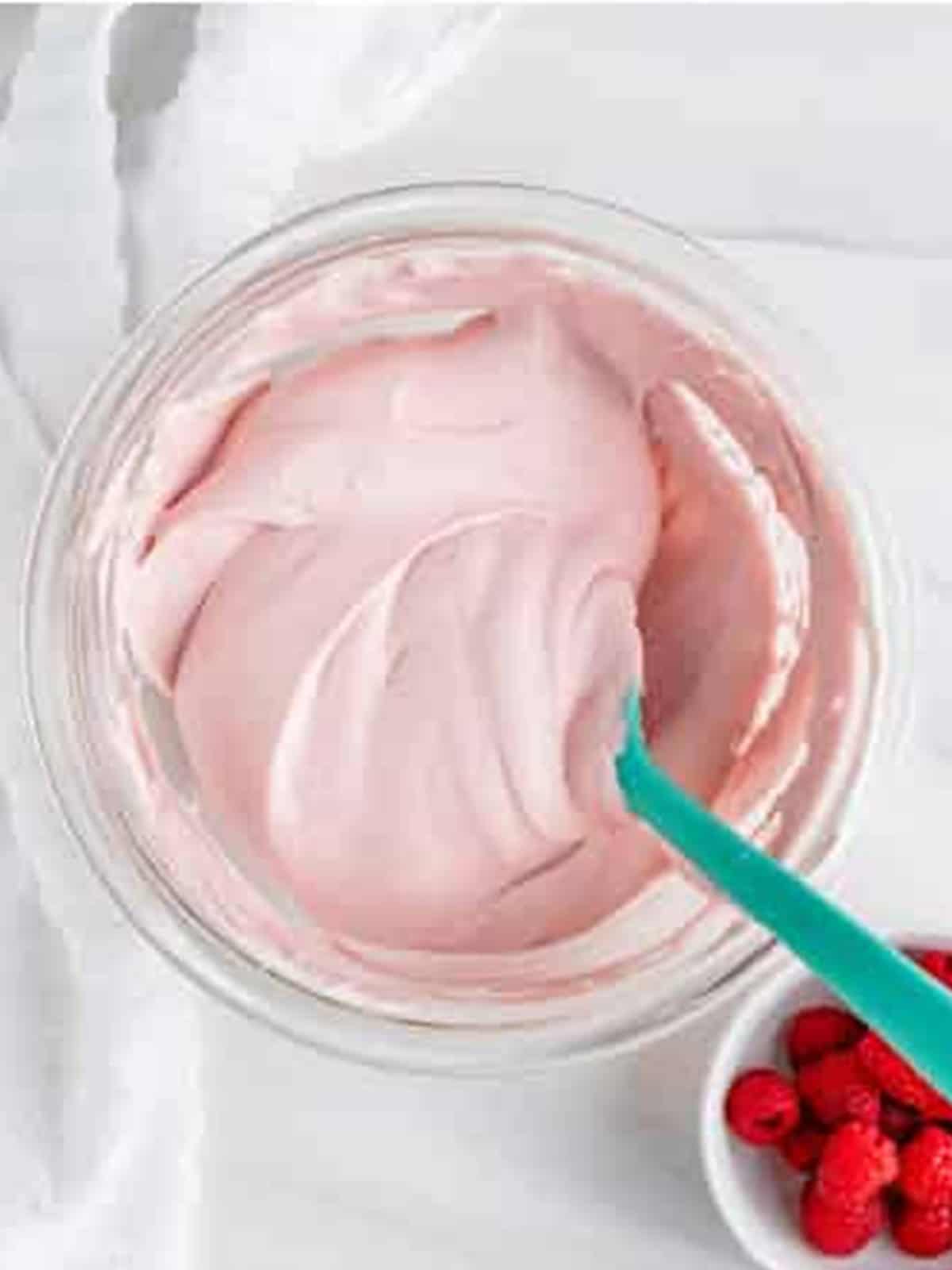 Raspberry preserves folded into whipped cream making pink cream for Raspberry Icebox Cake.