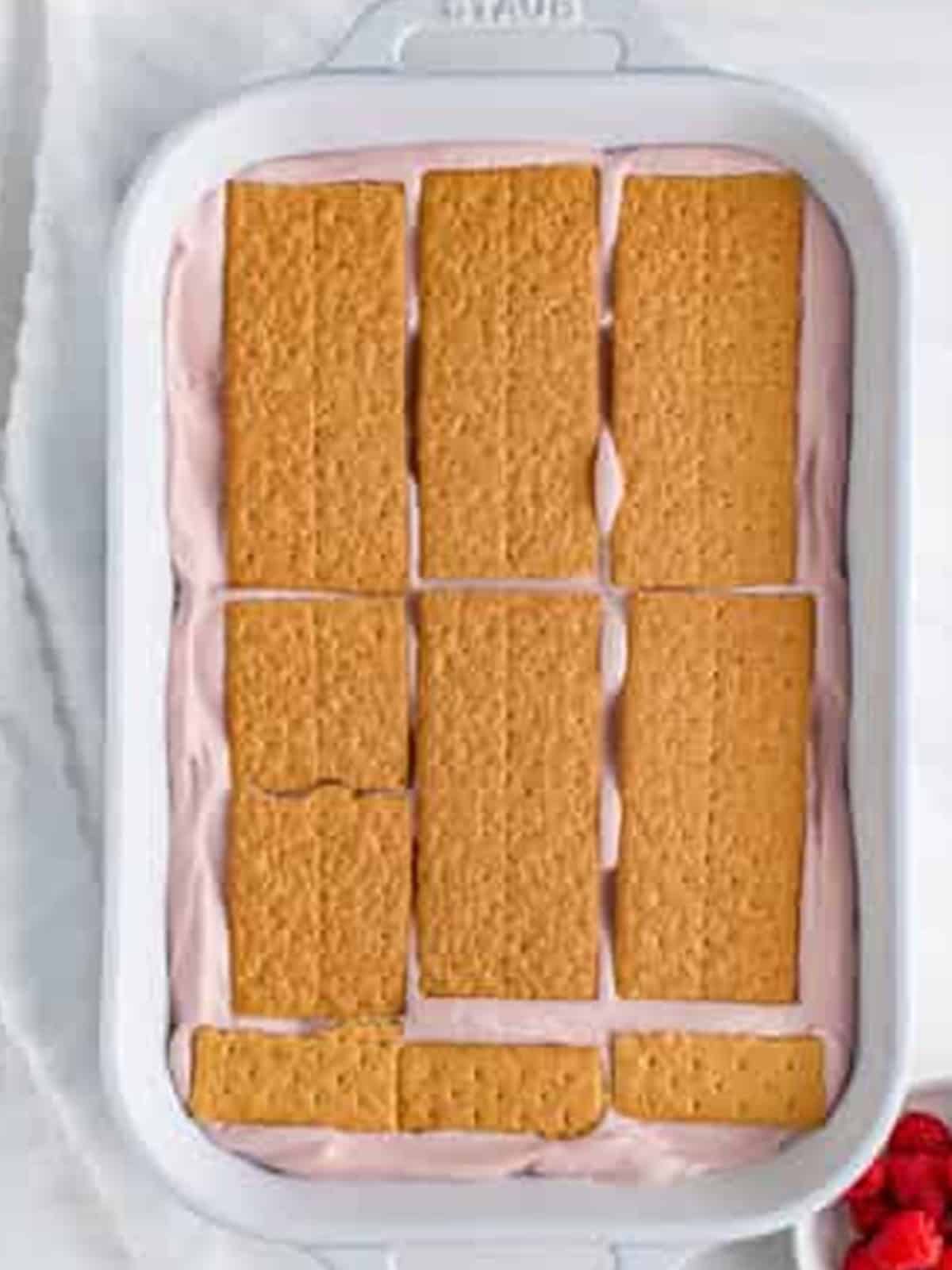 Third graham cracker layer placed over the pink cream for Raspberry Icebox Cake.