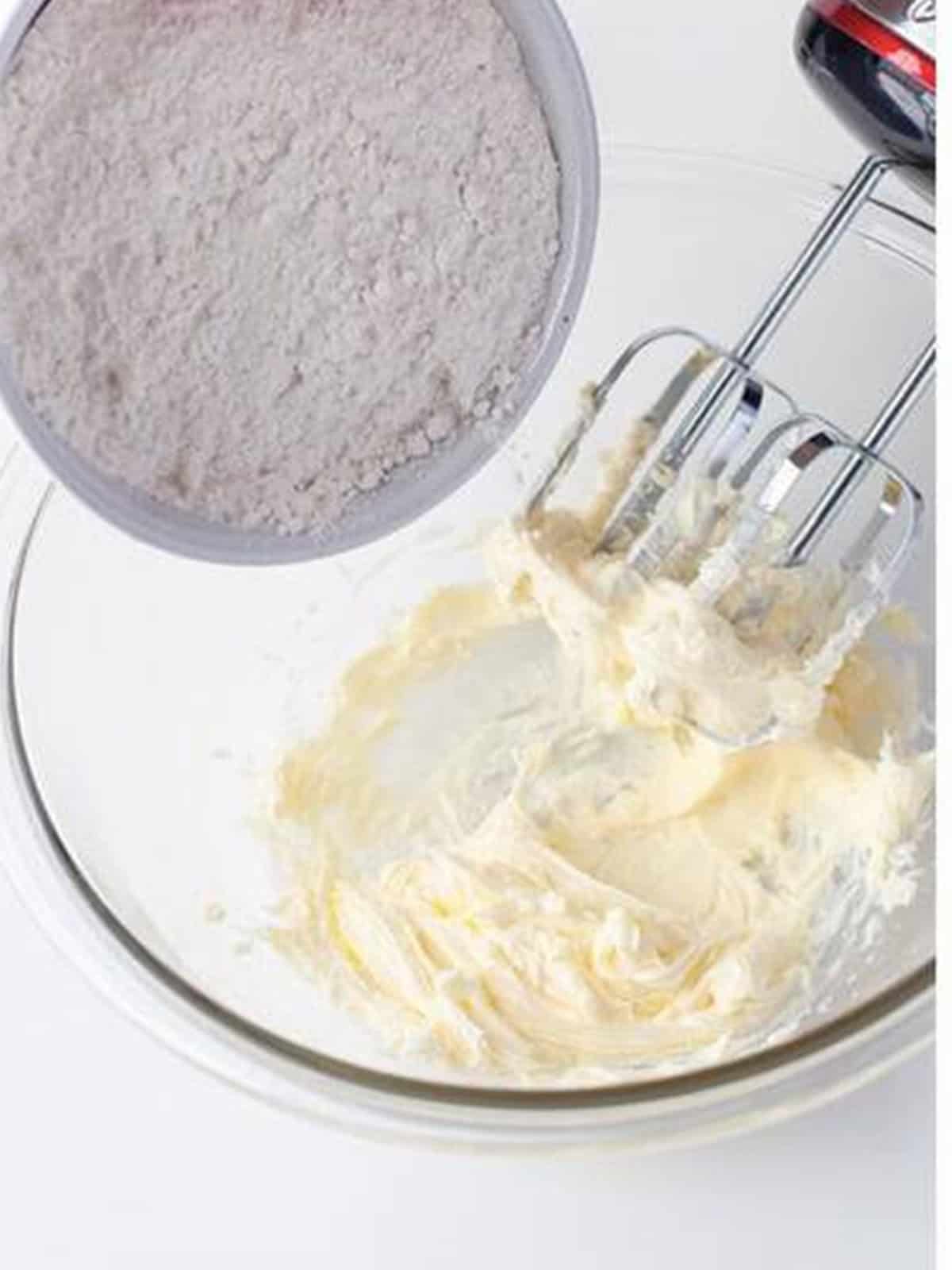 Flour added to creamed butter in a bowl to make tart dough.