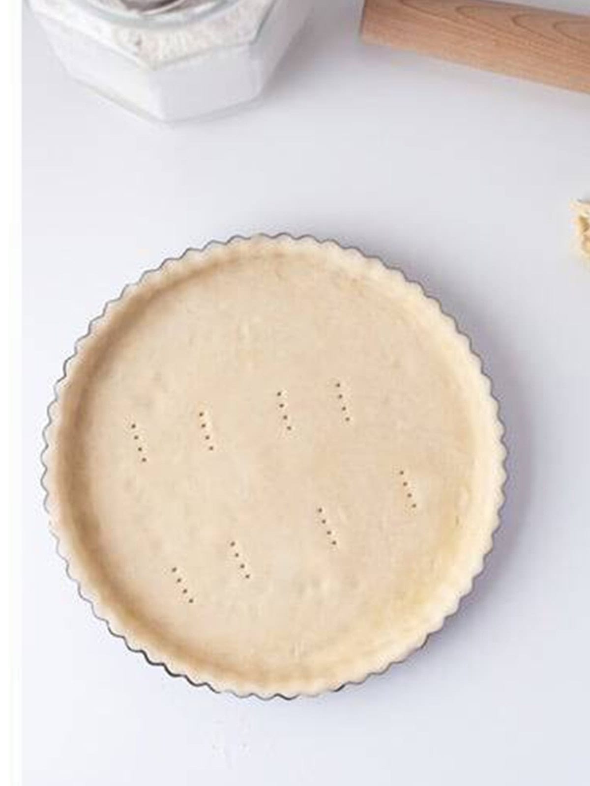 Tart dough pressed into a fluted tart pan and docked with a fork.
