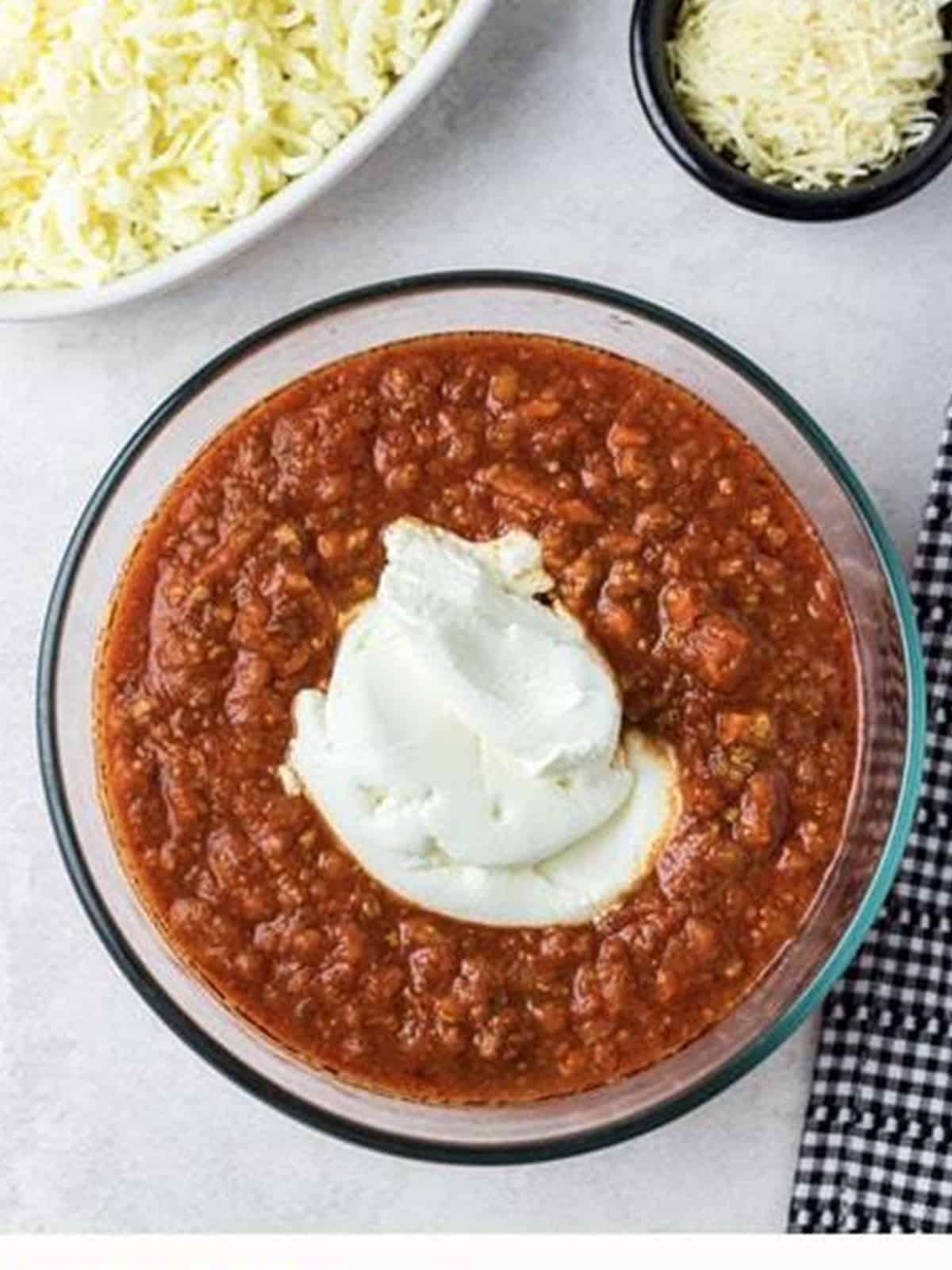Ricotta cheese added to a bowl of meat sauce.
