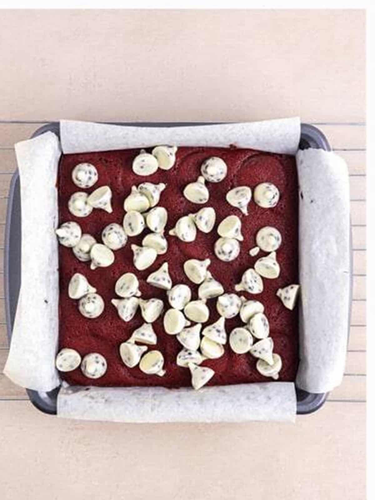 Cookies and cream kisses scattered over the warm baked Red Velvet Brownies.