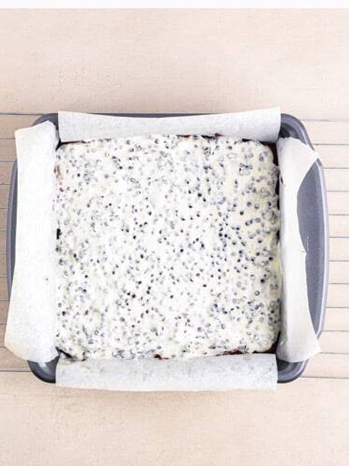 Melted cookies and cream topping smoothed over the Red Velvet Brownies.