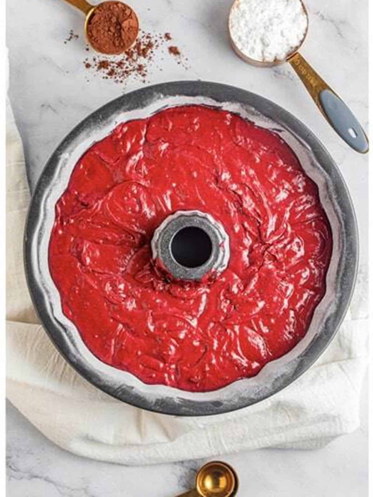 Red velvet batter poured into a greased bundt pan.
