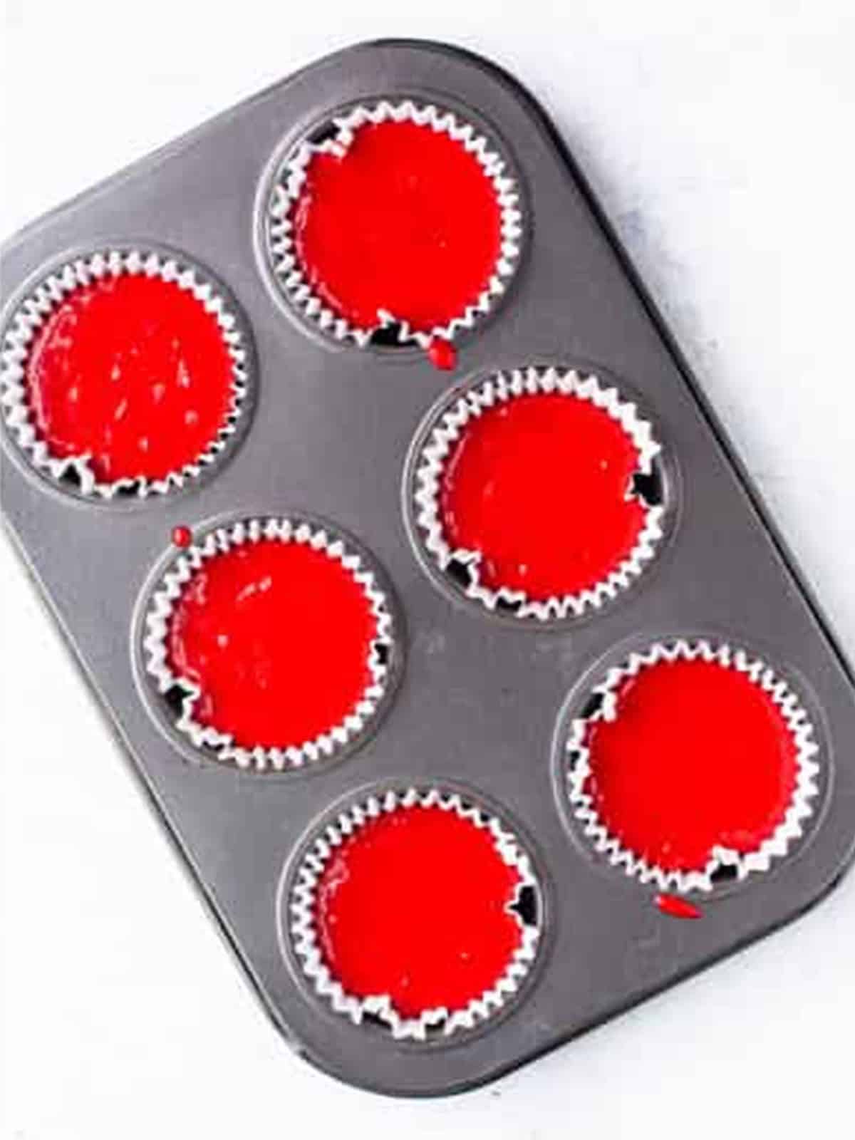 Baked red velvet cupcakes in the cupcake pan, ready to be frosted.