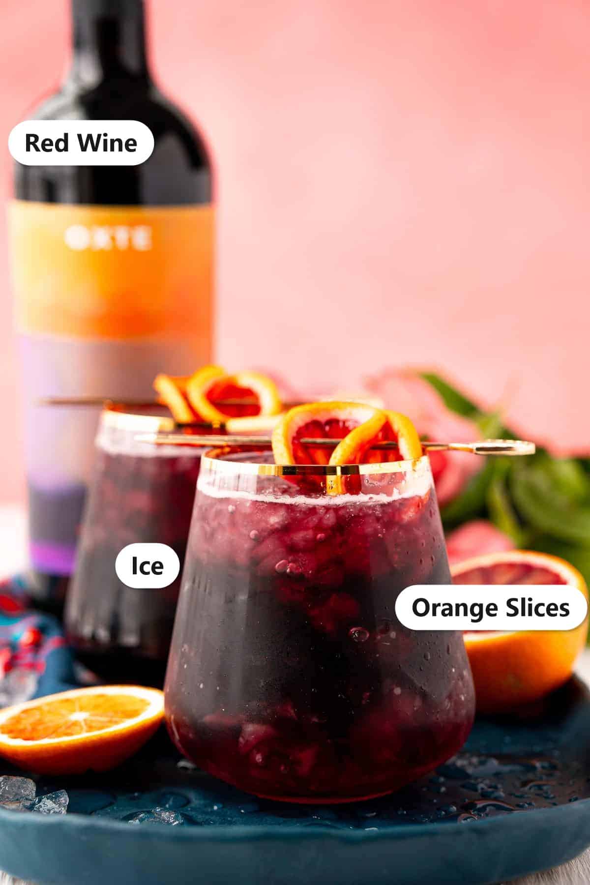 Red wine spritzer ingredients labeled including red wine, orange slices, and ice.